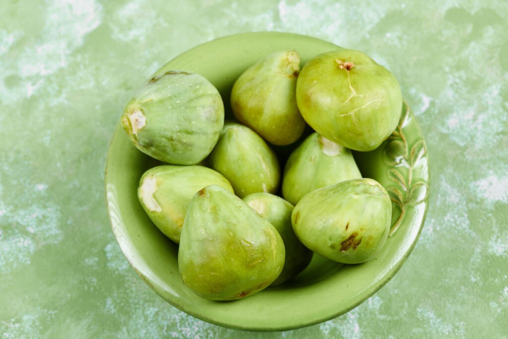 a bowl of juicy green figs on a green background